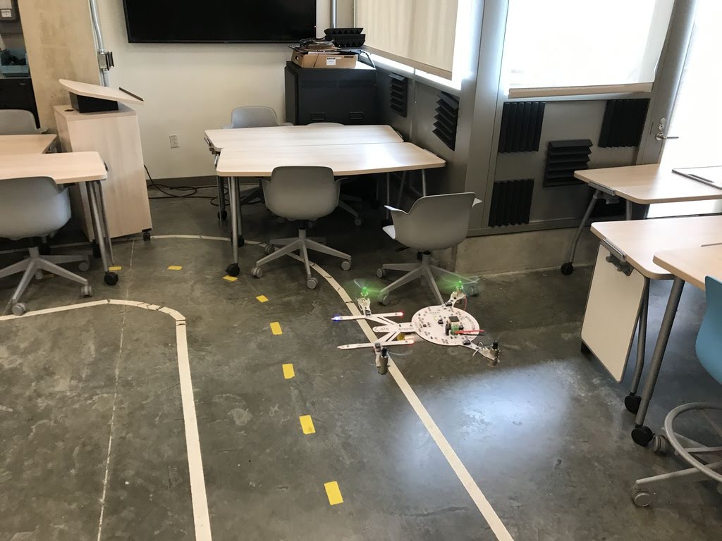 Quadcopter in the shape of the Starship Enterprise flying in a classroom